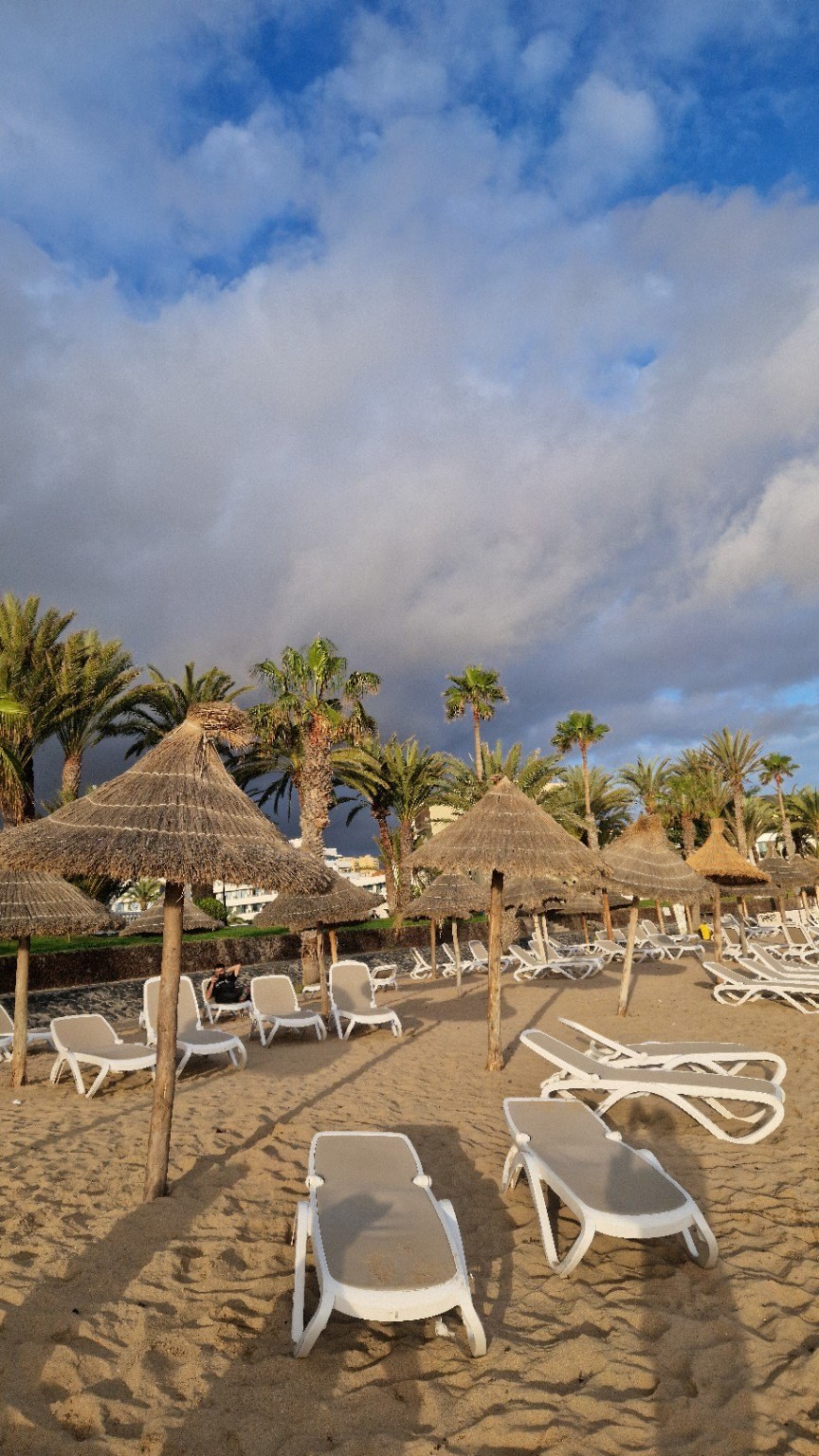 Beach with mostly empty sun loungers in the morning